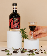 Nermin grape balsamic vinegar bottle beside a hand holding a small glass