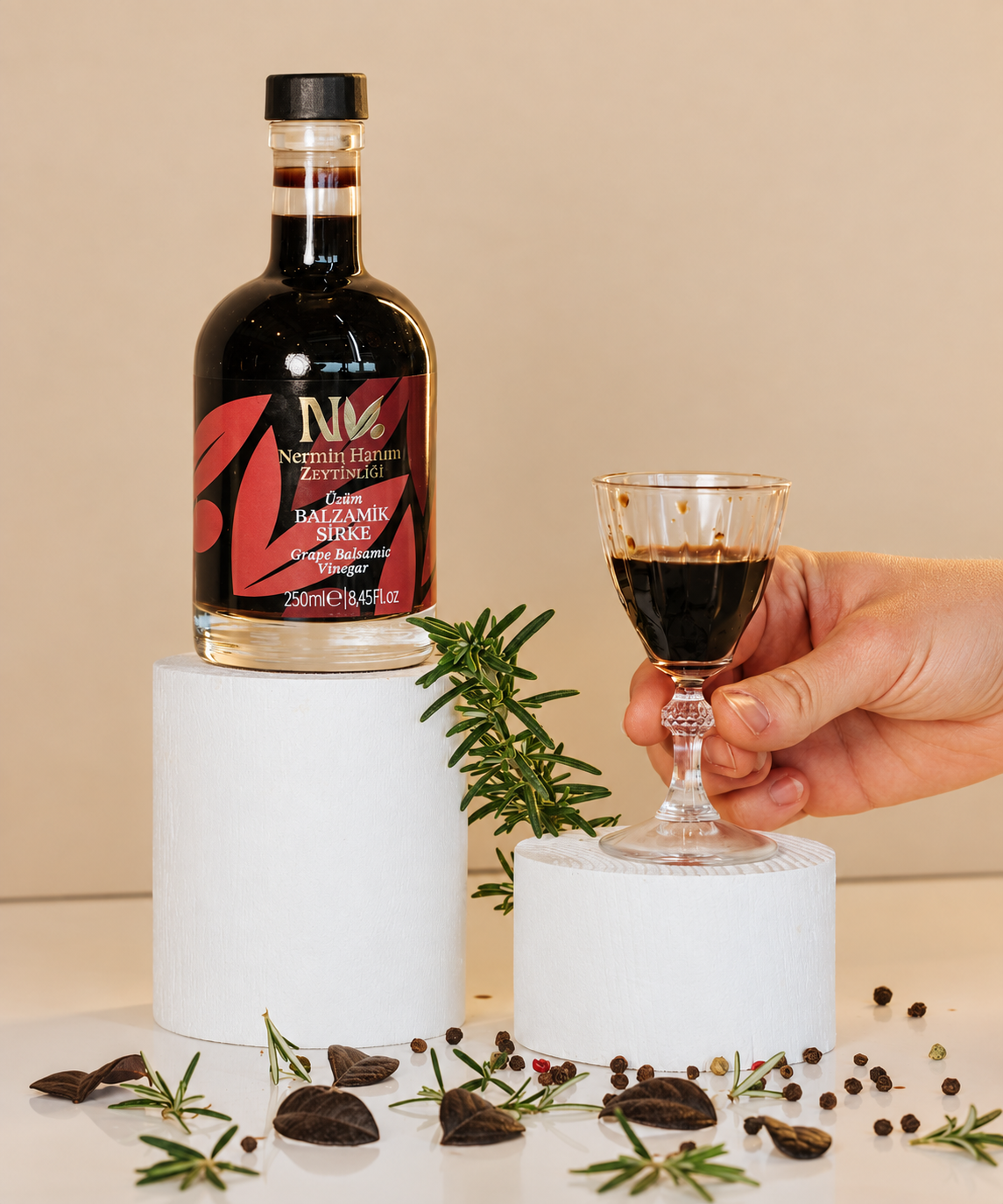 Nermin grape balsamic vinegar bottle beside a hand holding a small glass