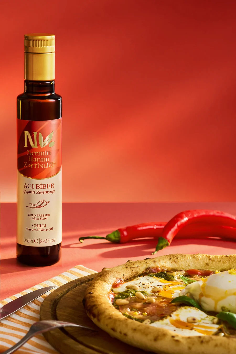Nermin chili flavored olive oil beside pizza and red chili peppers