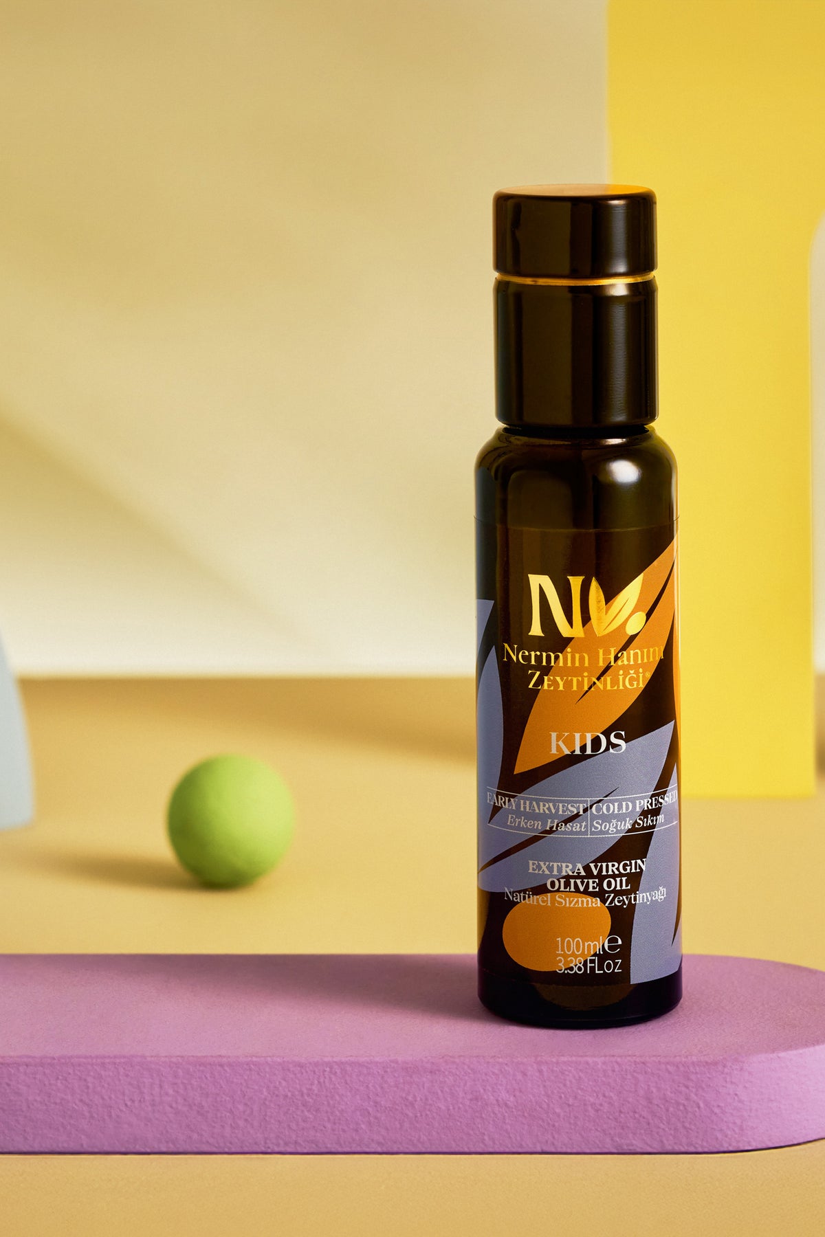 Nermin Kids olive oil bottle against a pastel yellow and purple background