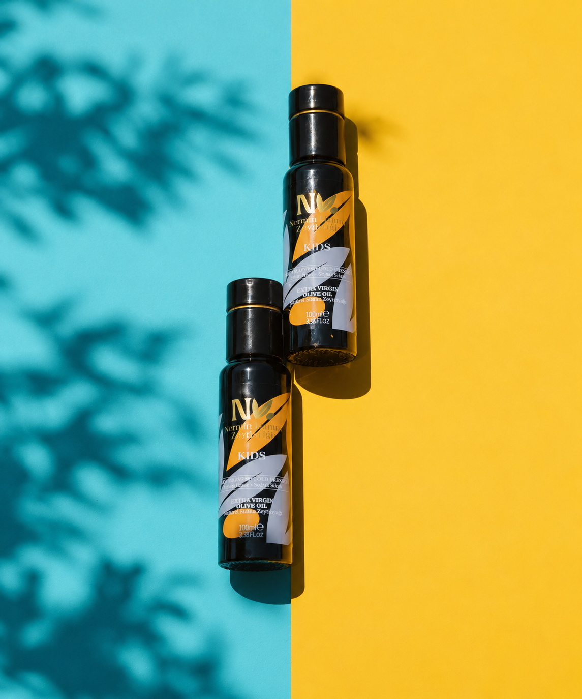 Two Nermin Kids olive oil bottles on a blue and yellow background