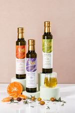 Nermin flavored olive oil bottles with citrus fruit, herbs and a glass of oil