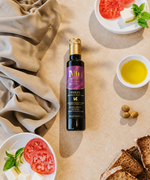 Nermin Trilye olive oil on a table with tomato, bread and a bowl of oil
